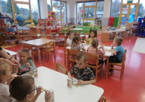 przedszkolaki jedzą ciastko i piją sok